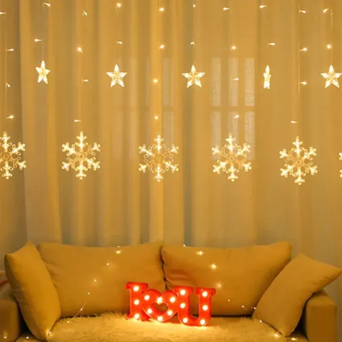 LED zavjesa sa svjetlećim pahuljama i zvjezdicama iznad kauča